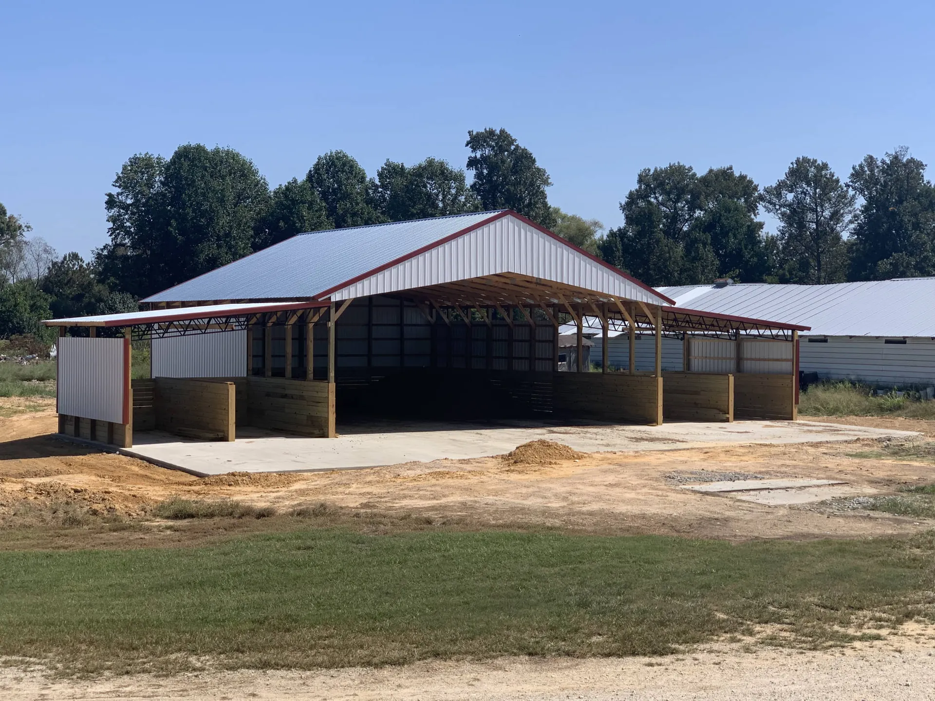 A metal barn with open sides and a white roof
