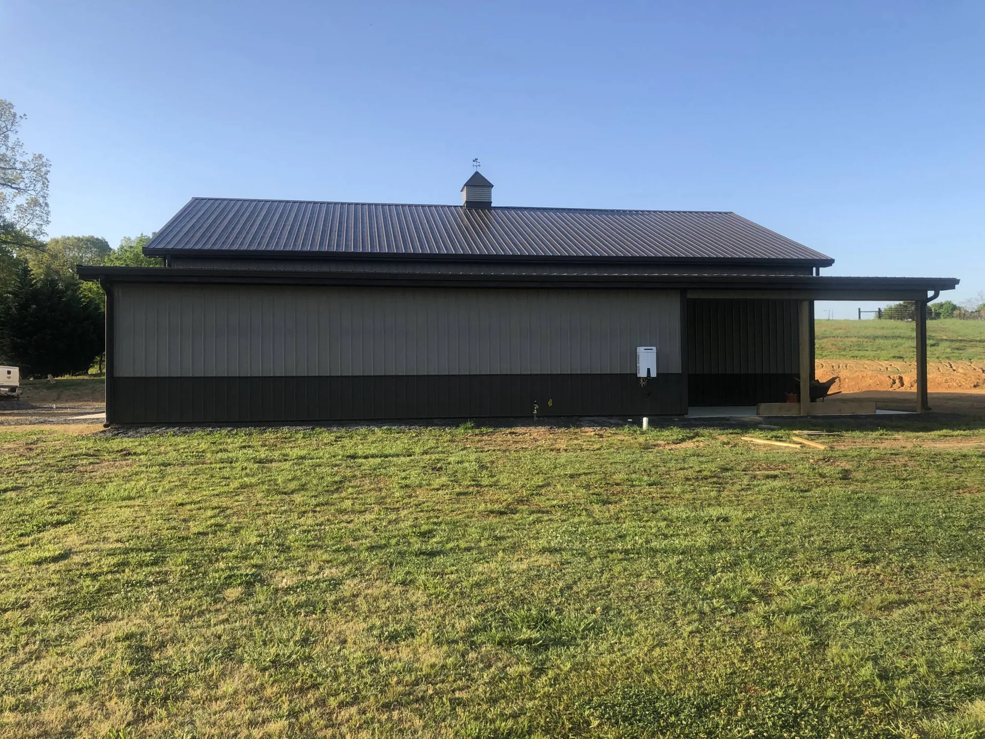 A dark metal commercial shop building beside a field