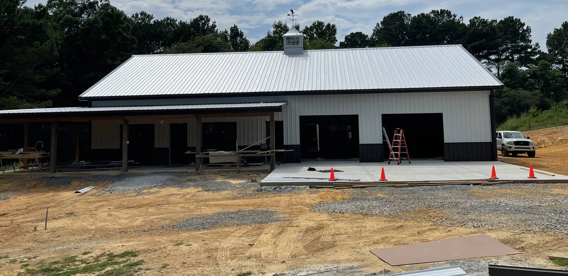 A white metal building with dark roof lines under construction