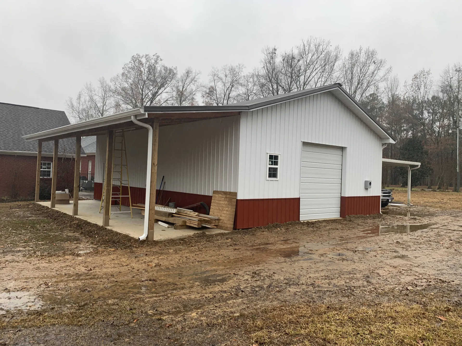A white metal building with a covered side porch