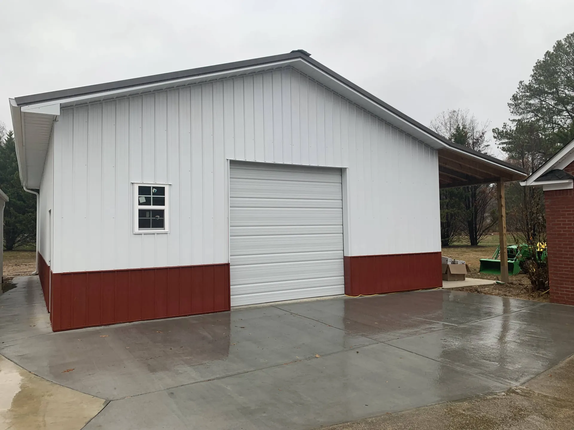 A white and red metal garage building with a roll-up door