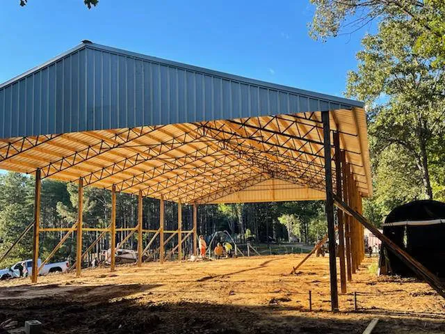 A pole barn with a green metal roof and timber framing