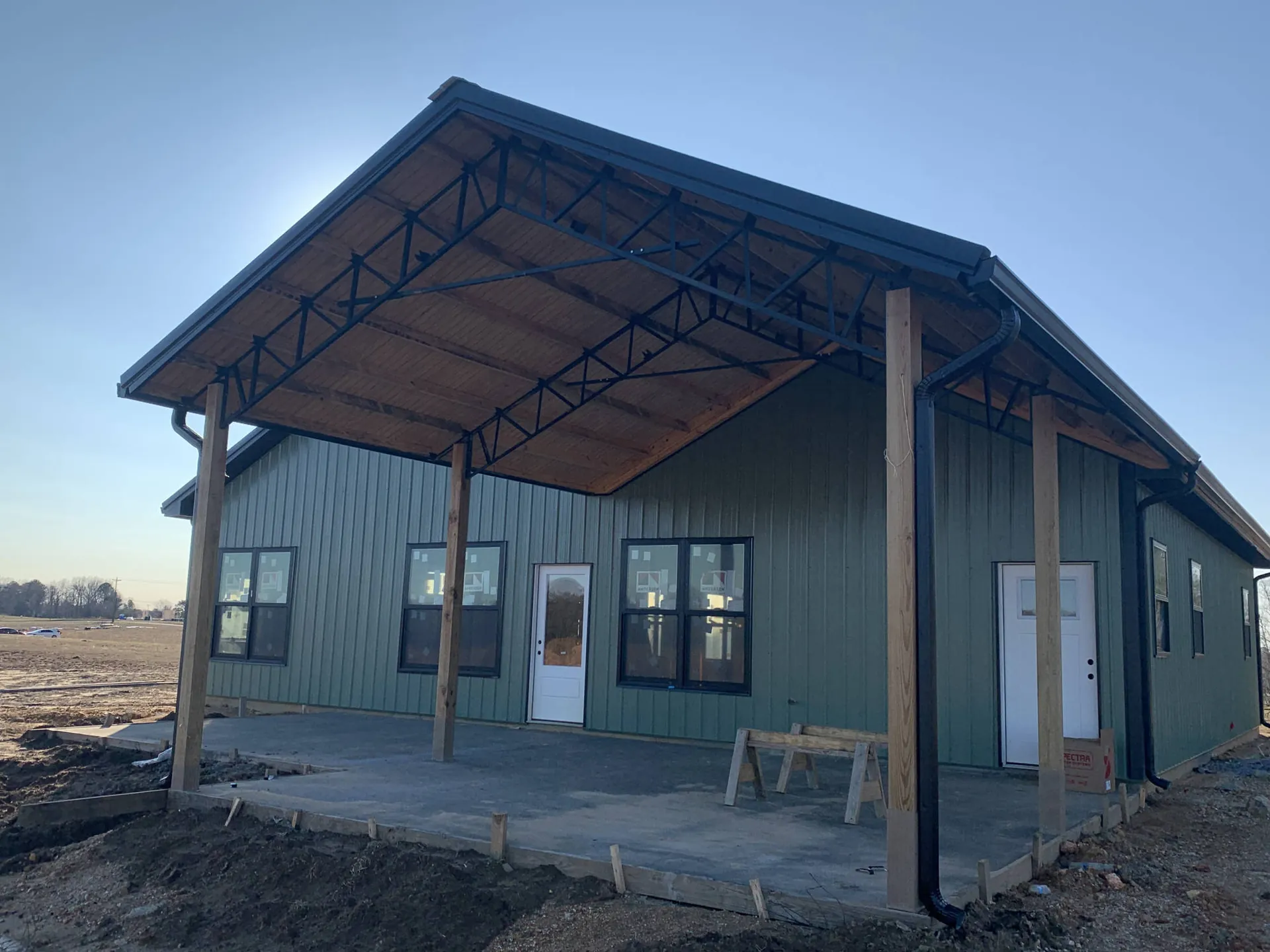 A green metal building with a timber-framed front porch