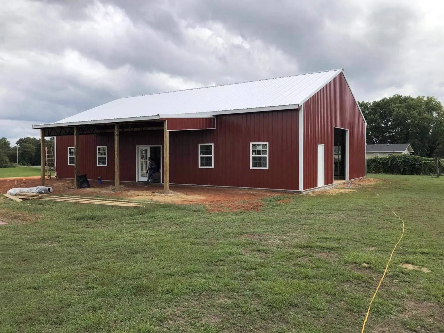 A red metal building with a wide porch and a barn door