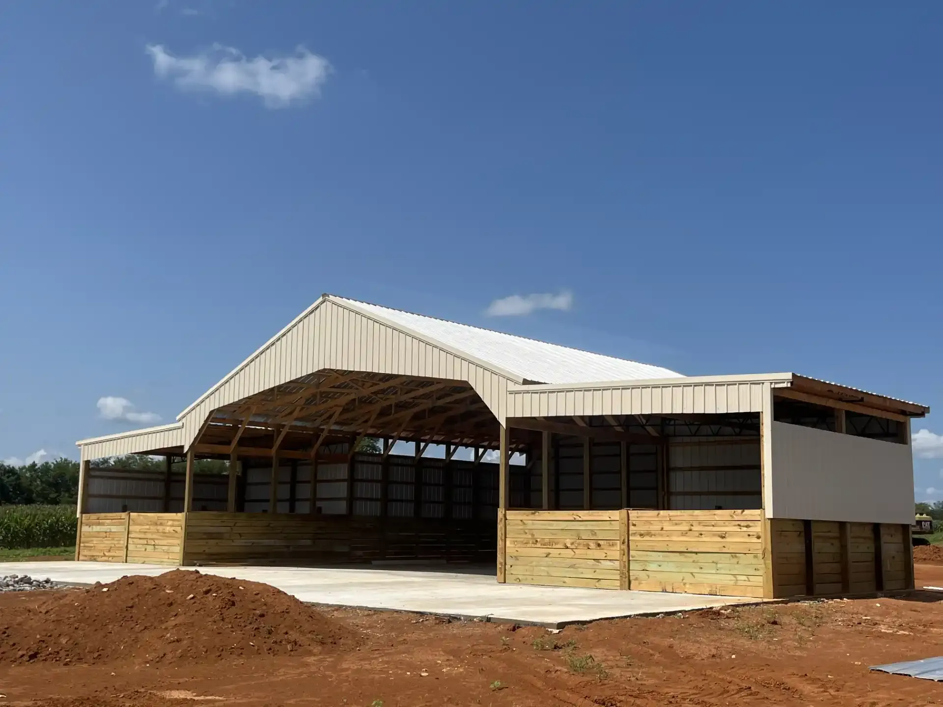 A pole building with a metal roof and wood framed stall bays