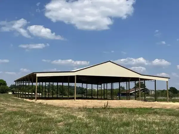 A long open-sided metal shelter on a gravel pad