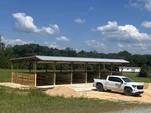 An open pole shelter with a work truck parked beside it